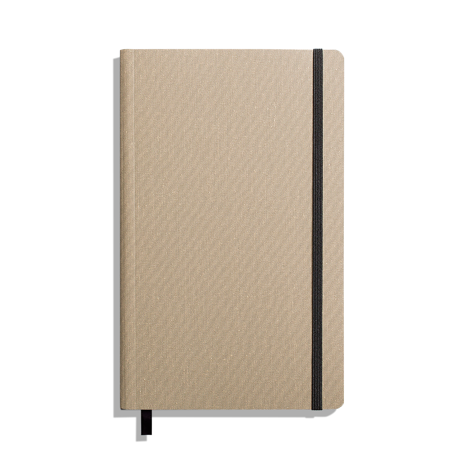 The Shinola Medium Soft Ruled Journal - Oat is shown closed with a textured beige cover, black elastic band on the right, and a black ribbon bookmark against a white background. Features durable smyth-sewn binding.