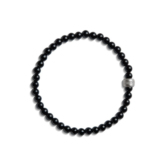 The Shinola 4mm Beaded Onyx Bracelet features small, round black onyx beads with a larger sterling silver accent bead engraved with text, shown on a white background.
