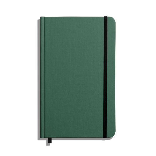 The Shinola Medium Hard Ruled Journal - Fern is a green linen, smyth-sewn notebook with a black elastic band and ribbon bookmark, shown from above on a white background.