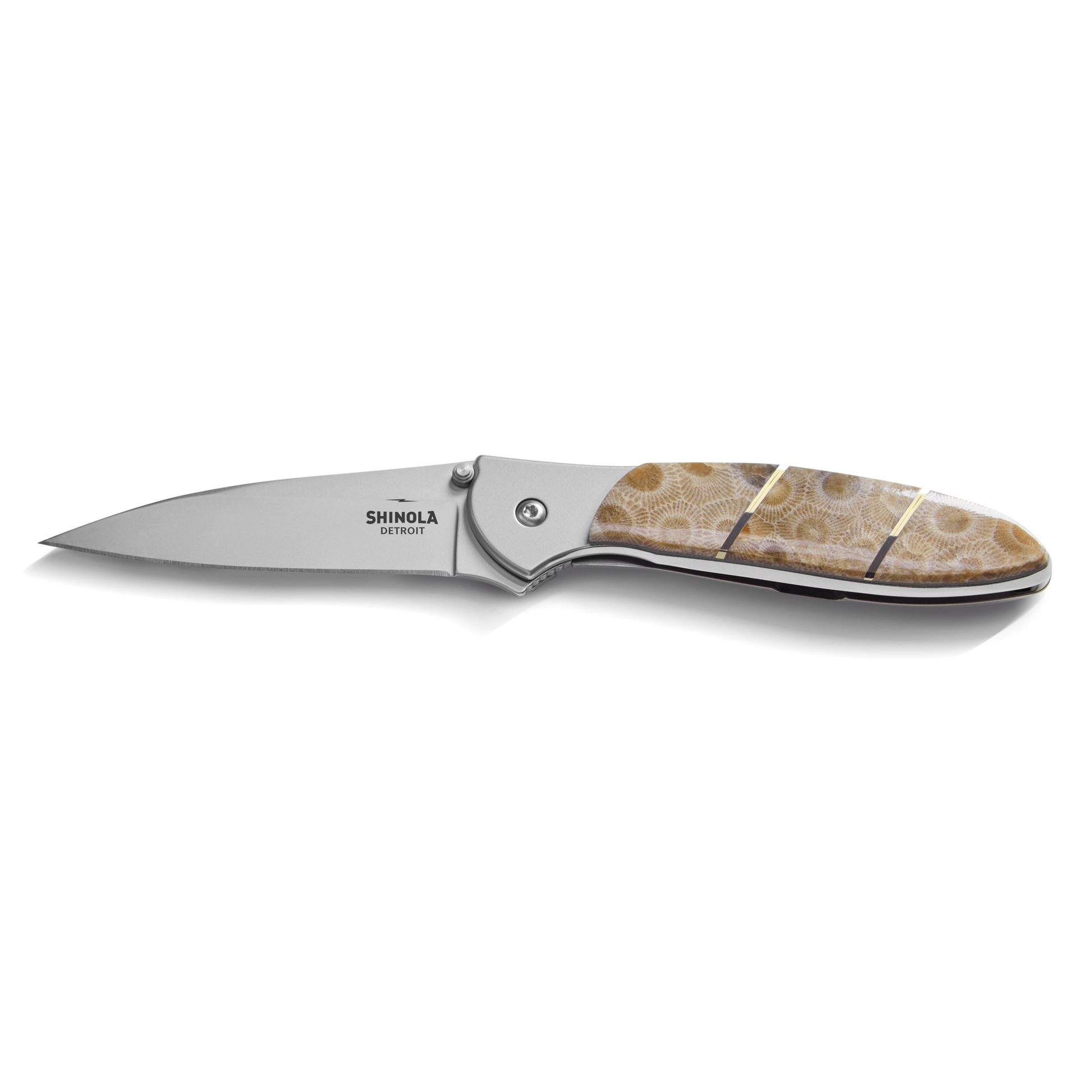 The Shinola + Kershaw Petoskey Stone Pocket Knife features a sharp silver blade and a beige-brown patterned Petoskey Stone handle, with Shinola branding near the hinge, shown on a white background.