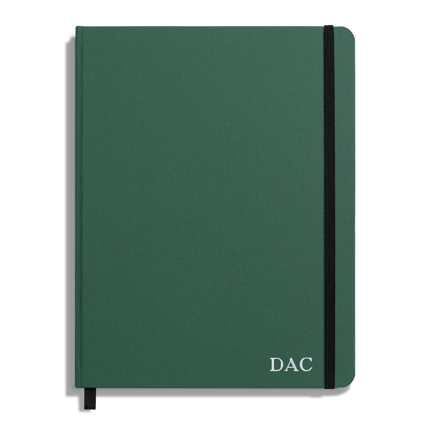 The Shinola Large Hard Ruled Journal - Fern is a green hardcover notebook with acid-free paper, black elastic band, black ribbon bookmark, and “DAC” in white on the lower right corner of the cover.