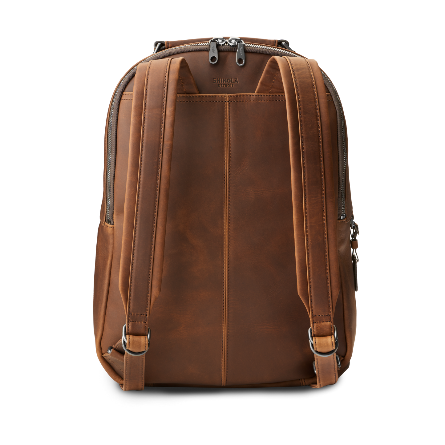 The Shinola Runwell Backpack in medium brown premium leather features two adjustable shoulder straps, a top handle, vertical stitching, and a top zipper, shown here from the back.
