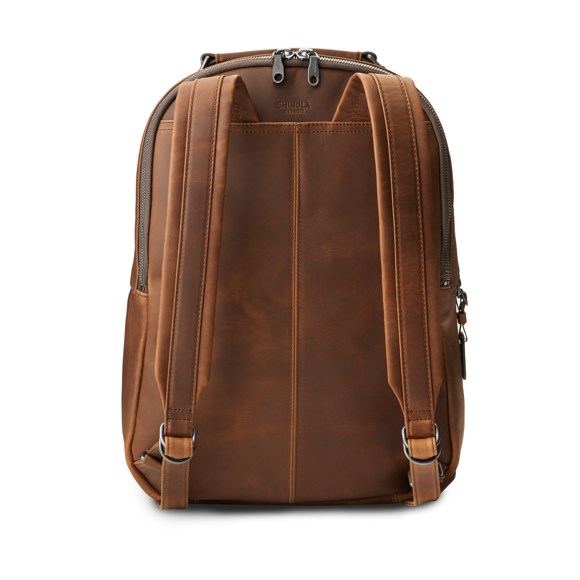 The Shinola Runwell Backpack in medium brown premium leather features two adjustable shoulder straps, a top handle, vertical stitching, and a top zipper, shown here from the back.