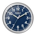 A 14" Shinola Runwell Clock in navy, featuring a round design with a blue face, white numbers, and silver frame. The clock displays 10:10:34 with "Shinola Detroit" below the 12 o'clock mark.