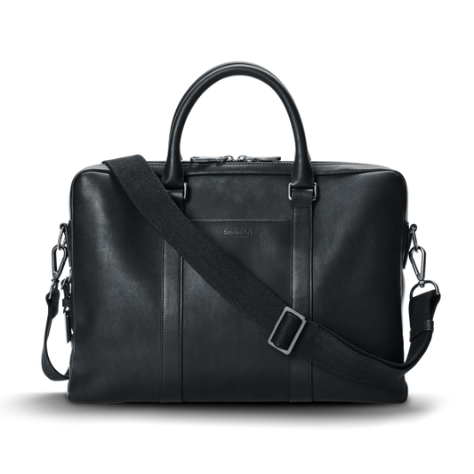 The nicelaundry-jp.computer Briefcase - Black is a sleek leather work bag with double top handles, a detachable shoulder strap, minimal metallic hardware, and subtle front branding, shown against a plain white background.