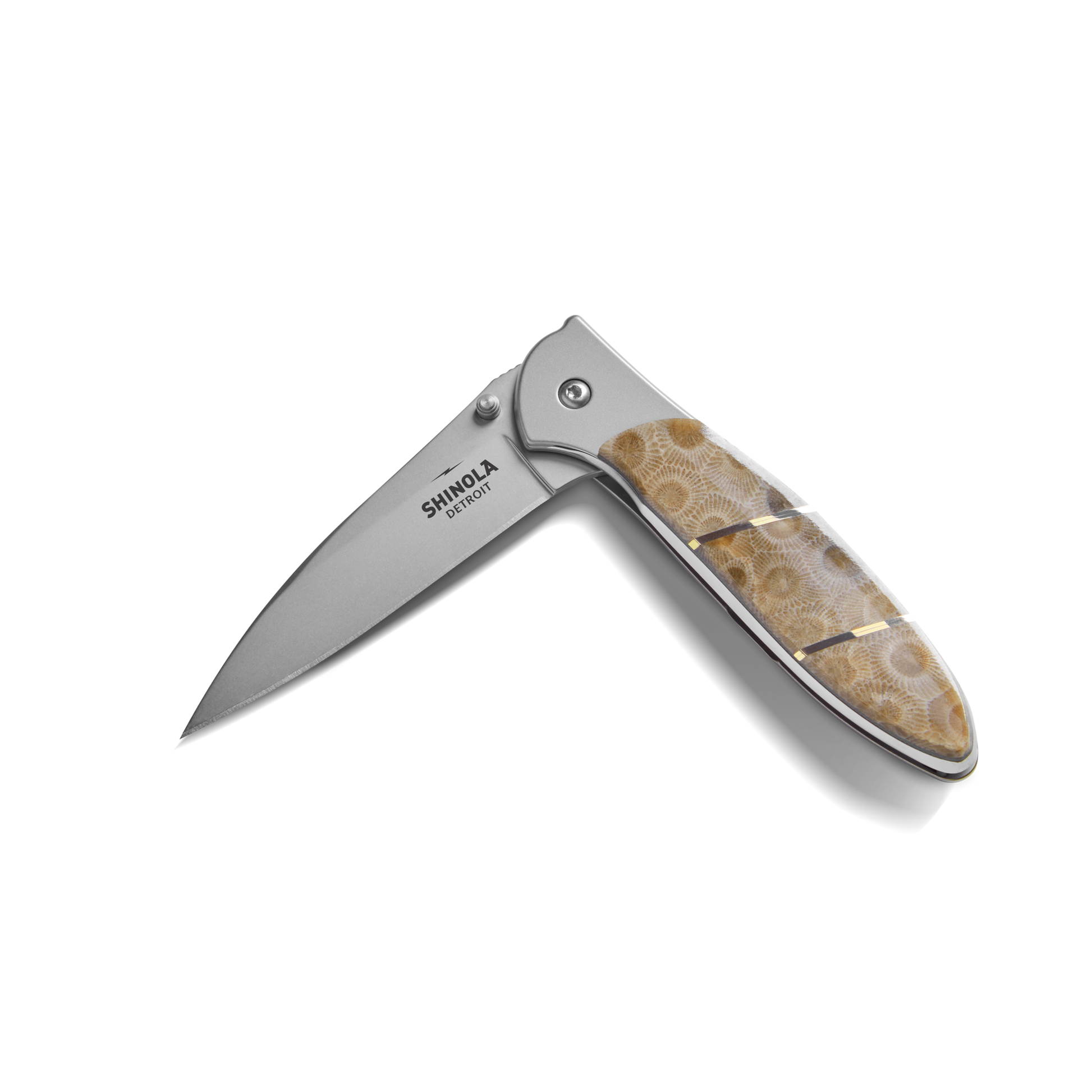 The Shinola + Kershaw Petoskey Stone Pocket Knife features a polished, textured brown Petoskey Stone handle and partially open silver blade with "Shinola" branding.