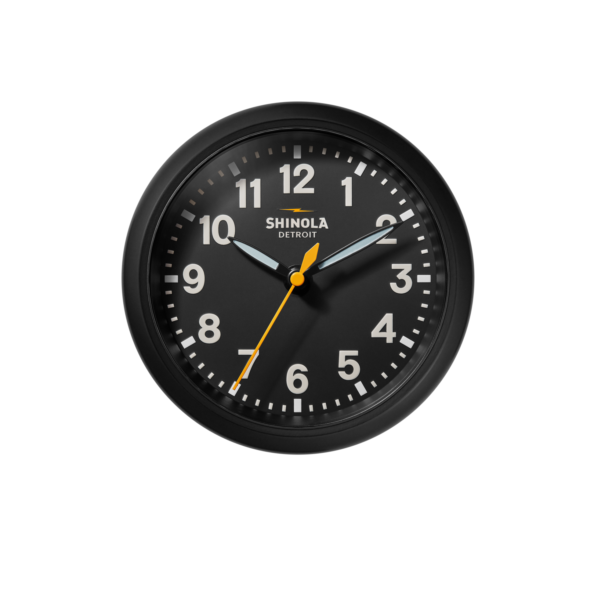 The 6" Runwell Clock - Black by Shinola features a round black face, white numbers and hands, an orange second hand, and displays the time as 2:10:32. Inspired by the Detroit watch factory.